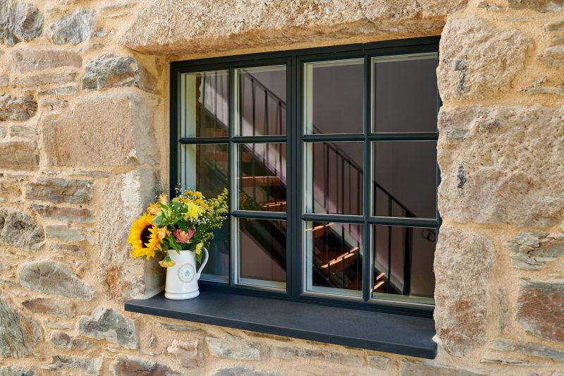 Rationel window with black aluminium frame and yellow flowers in vase