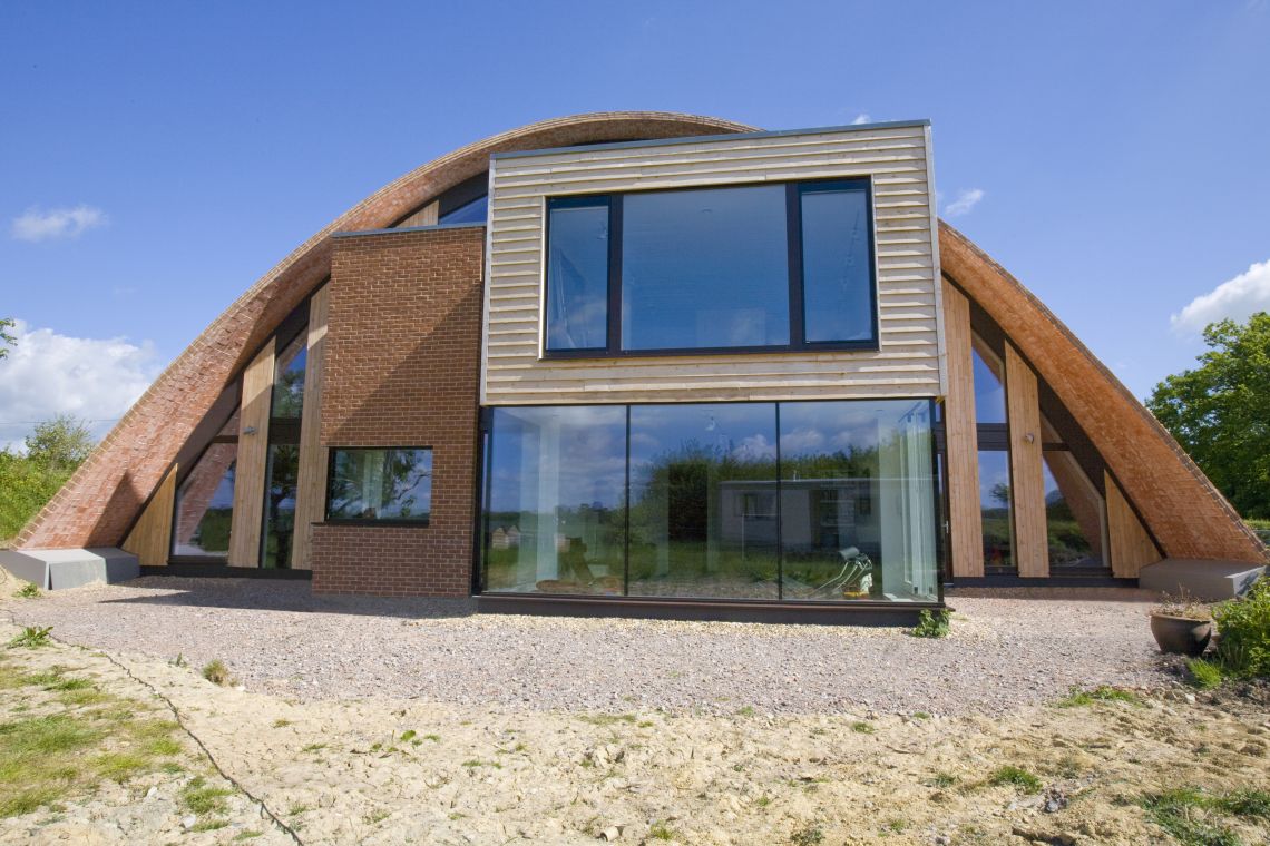 Crossways Passivhaus project - view of home with wooden arching roof and large glass windows