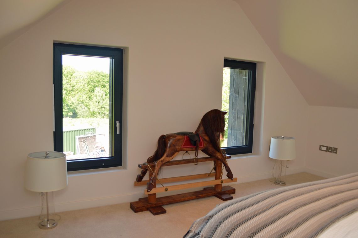 A rocking horse in a bedroom with two lamps either side of it.
