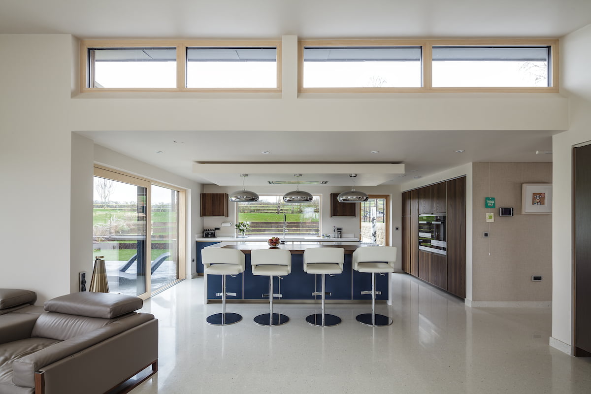 An open plan kitchen and living area with a breakfast bar and four stools.