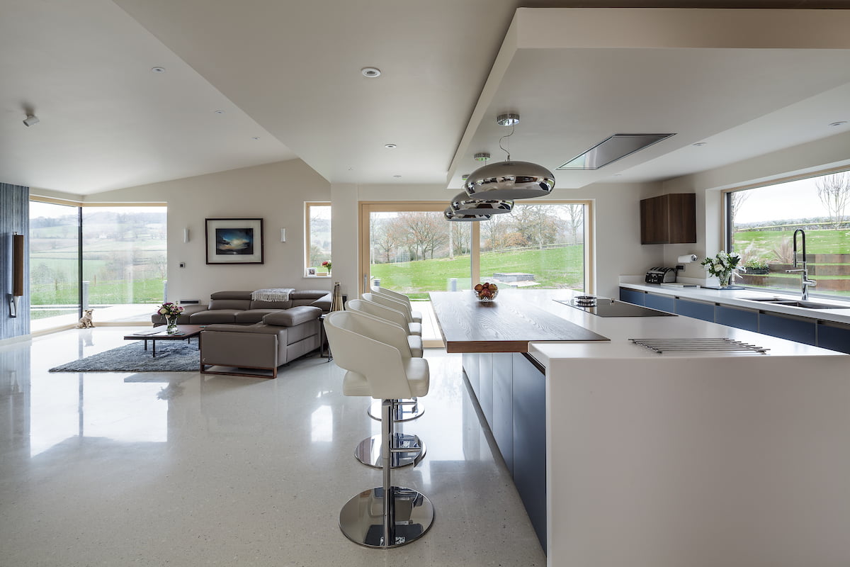 A large open-plan house with a kitchen and breakfast bar on the right and a sofa area on the left.