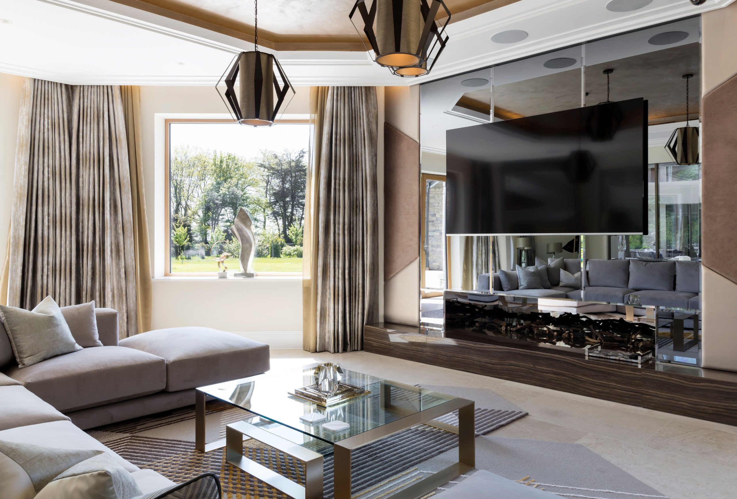 A room with a TV, sofas, glass table