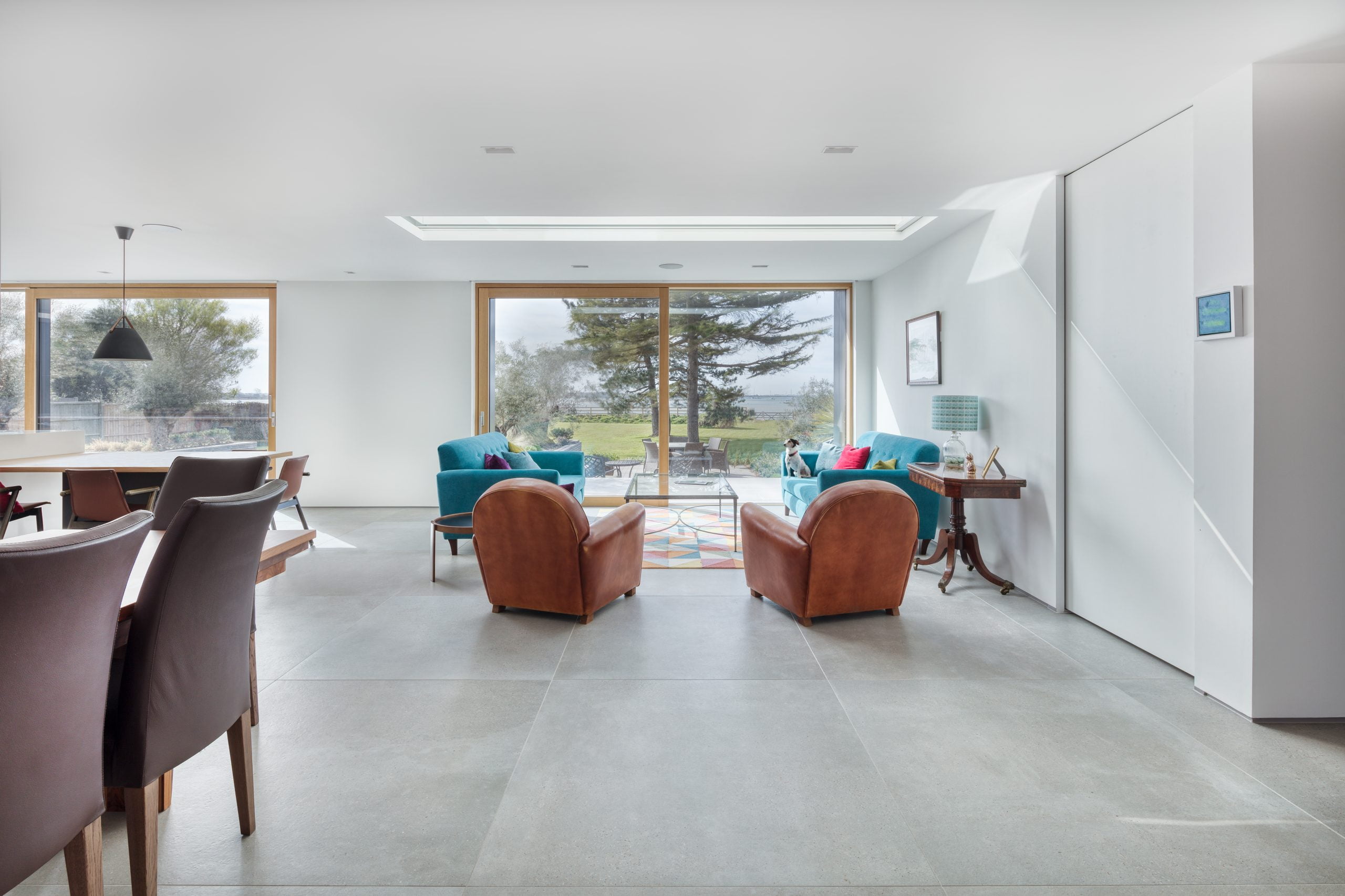 A large living space with two green sofas and two tan leather armchairs.