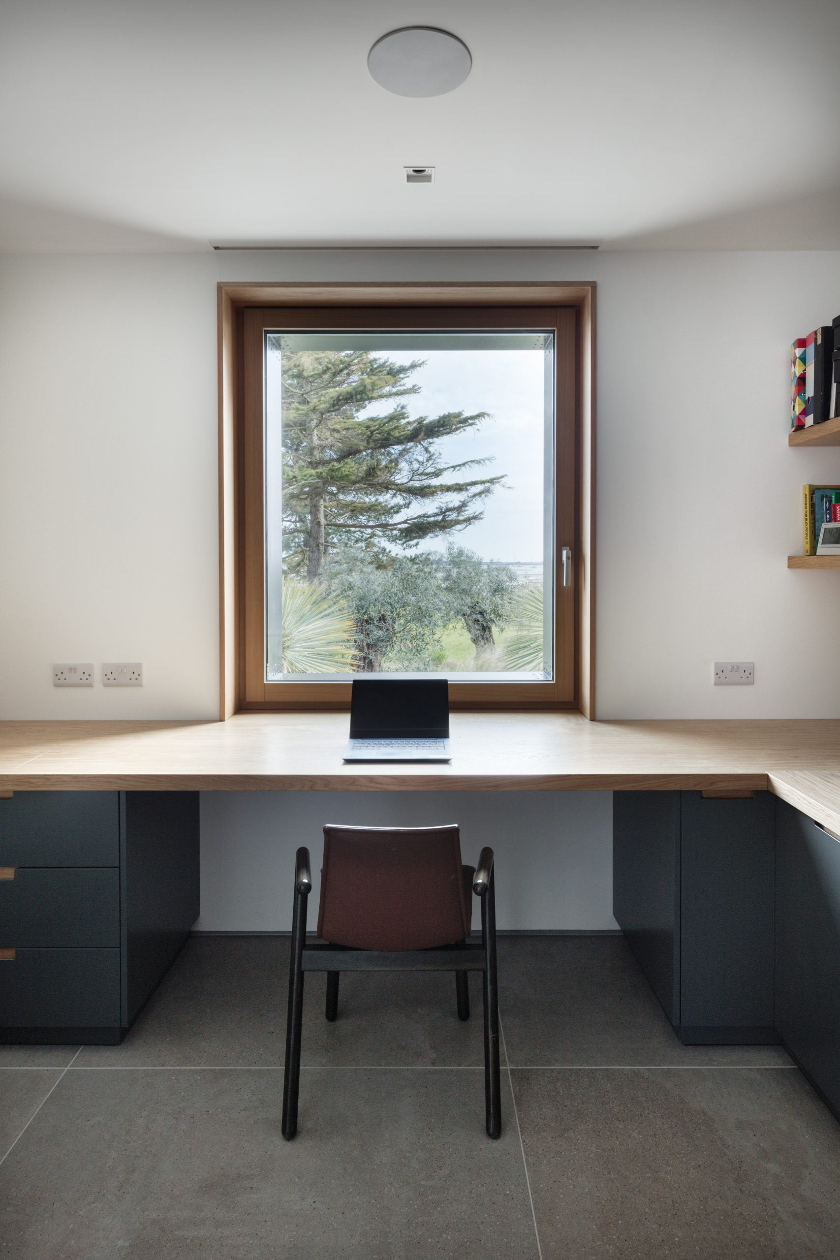 A corner desk with a single laptop on top of it and a chair pushed underneath it.